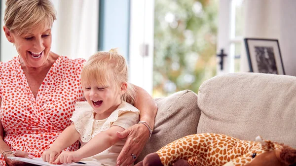 Großmutter Sitzt Mit Enkelin Hause Auf Sofa Und Liest Gemeinsam — Stockfoto