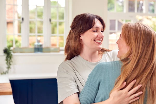 Twee Vrouwelijke Vrienden Groeten Knuffelen Keuken Thuis — Stockfoto