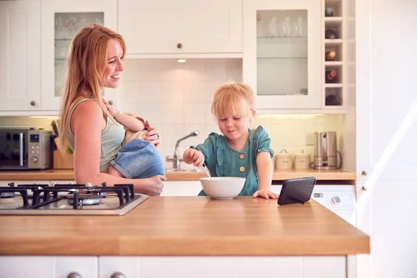 Chica Mostrador Cocina Comiendo Desayuno Viendo Teléfono Móvil Mientras Madre —  Fotos de Stock