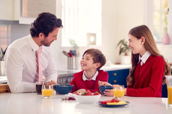 仕事の前に制服を着た子供たちと朝食を取る父 — ストック写真