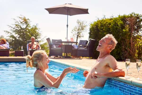 Senior Pár Důchodu Odpočinek Bazénu Letní Dovolenou Cákání Navzájem — Stock fotografie