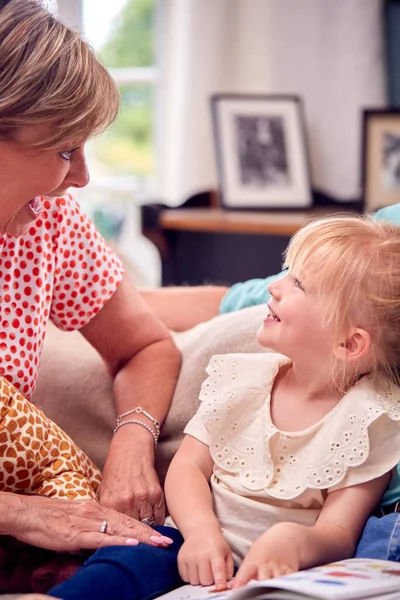 Großeltern Sitzen Mit Enkelin Hause Auf Sofa Und Lesen Gemeinsam — Stockfoto