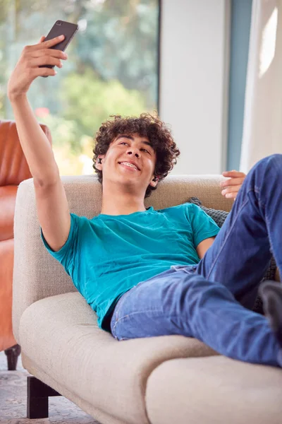 Tonårspojke Ligger Soffan Hemma Med Selfie För Sociala Medier Mobiltelefon — Stockfoto