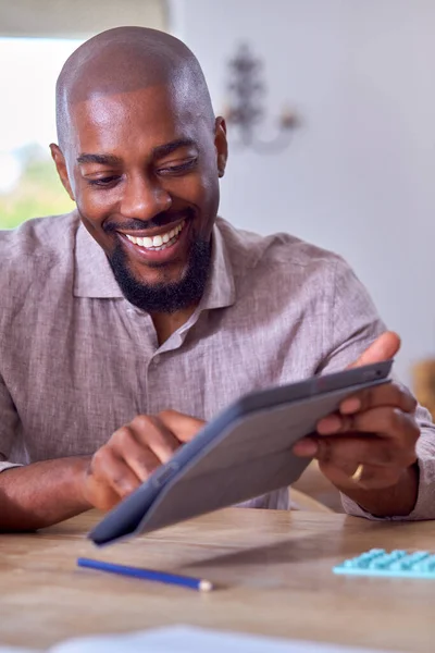 Homem Sorridente Sentado Mesa Casa Usando Tablet Digital — Fotografia de Stock