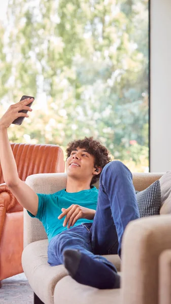 Dospívající Chlapec Ležící Pohovce Doma Přičemž Selfie Pro Sociální Média — Stock fotografie