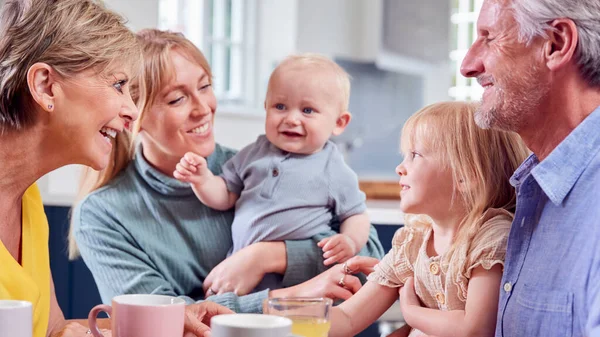 Morföräldrar Med Vuxen Dotter Och Barnbarn Sitter Runt Köksbordet Hemma — Stockfoto