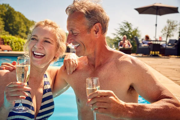 退休长者在泳池内放松心情庆祝暑假喝香槟 — 图库照片