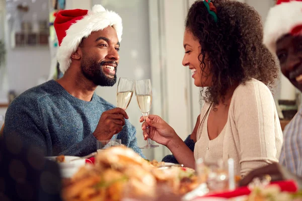 紙の中で複数世代の家族としてトーストを作るカップル自宅でクリスマスの食事を楽しむ帽子 — ストック写真