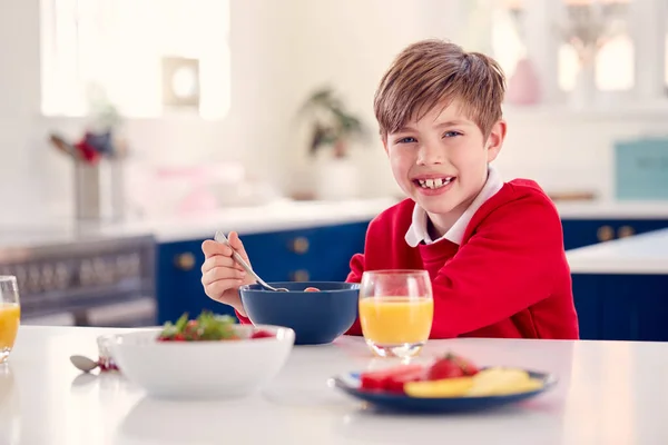 Смеющийся Мальчик Школьной Форме Кухне Ест Здоровый Завтрак Свежей Клубникой — стоковое фото