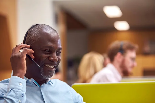 Érett Üzletember Aki Telefonfülhallgatót Visel Beszél Telefonálóval Forgalmas Ügyfélszolgálati Központban — Stock Fotó