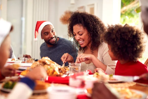 Familia Papel Sombreros Disfrutando Comer Comida Navidad Casa Juntos —  Fotos de Stock