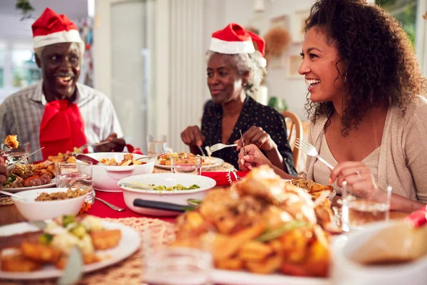 Multi Generation Rodzina Papierowych Kapeluszach Korzystających Jedzenie Świąteczne Posiłek Domu — Zdjęcie stockowe