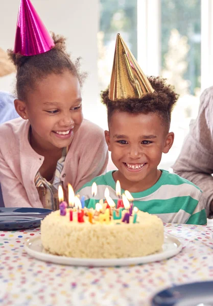 男の子と女の子がケーキと家族のパーティーで男の子の誕生日を祝う家のテーブルの周りに座って — ストック写真