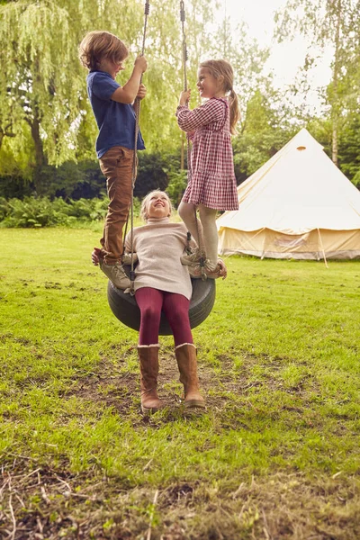 Drei Kinder Spielen Auf Reifenschaukel Heimischen Garten Mit Zelt Hintergrund — Stockfoto