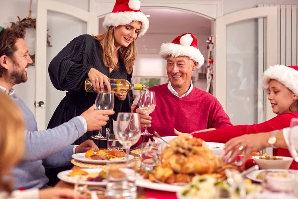 Madre Vertiendo Vino Como Familia Multigeneracional Comen Comida Navidad Juntos —  Fotos de Stock
