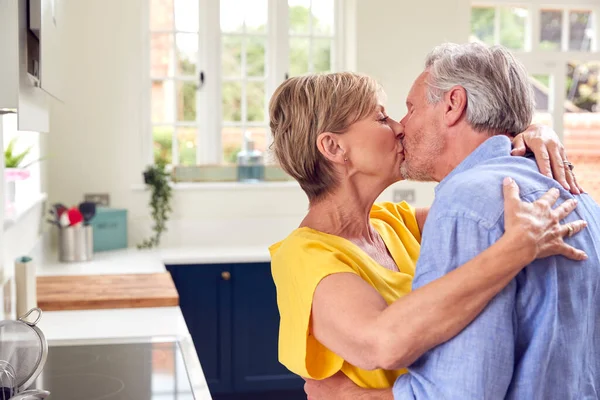 Loving Retired Couple Hugging Kissing Kitchen Home Together — Stock Photo, Image