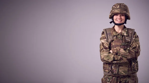 平面的な背景を背景にした軍事制服で笑顔若い女性兵士のスタジオ肖像画 — ストック写真