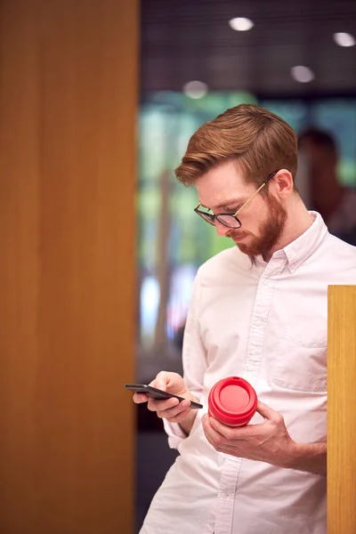 オフィスで休憩中のビジネスマンは 再利用可能なコーヒーカップを保持し 携帯電話を見て — ストック写真