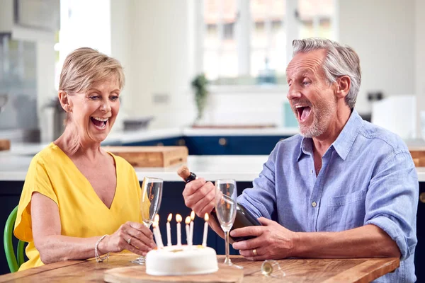 シャンパンとケーキのグラスで誕生日を祝う退職したカップルが一緒に家で — ストック写真
