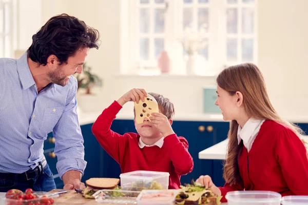 学校の制服を着た子供たちと一緒に家で昼食のために健康的なサンドイッチを作る楽しみ — ストック写真
