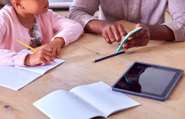 父亲帮助女儿在家上学坐到桌旁用数字记事板 — 图库照片