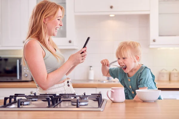 Menina Balcão Cozinha Comer Café Manhã Enquanto Mãe Usa Telefone — Fotografia de Stock