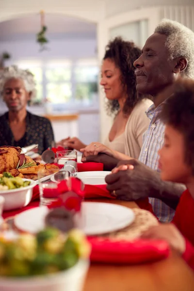 クリスマスの食事を食べる前に恵みと言って自宅でテーブルの周りにマルチ世代の家族の手 — ストック写真