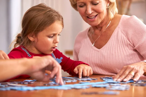 Vnučka Babičkou Sedí Kolem Stolu Doma Dělá Puzzle Spolu — Stock fotografie