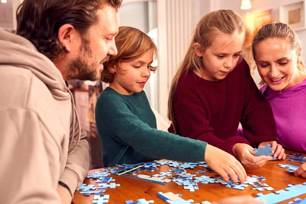 Famiglia Seduta Intorno Tavolo Casa Facendo Puzzle Insieme — Foto Stock