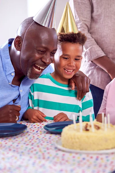 ケーキやパーティーで男の子の誕生日を祝う自宅でテーブルの周りに座っているマルチ世代の家族 — ストック写真