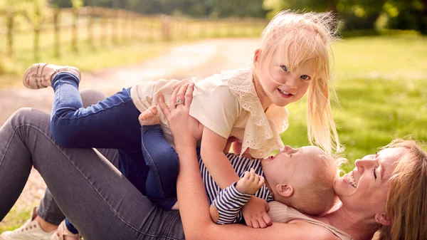 Mãe Filhos Divertindo Livre Com Crianças Deitadas Cima Dela Grama — Fotografia de Stock