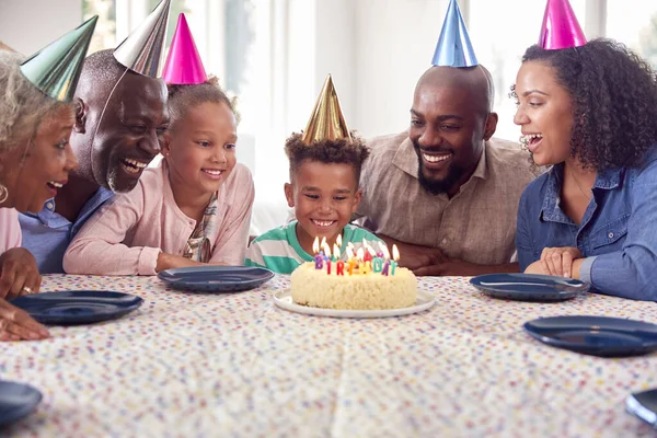 Multi Generation Rodzina Siedzi Wokół Stołu Domu Świętując Urodziny Chłopca — Zdjęcie stockowe