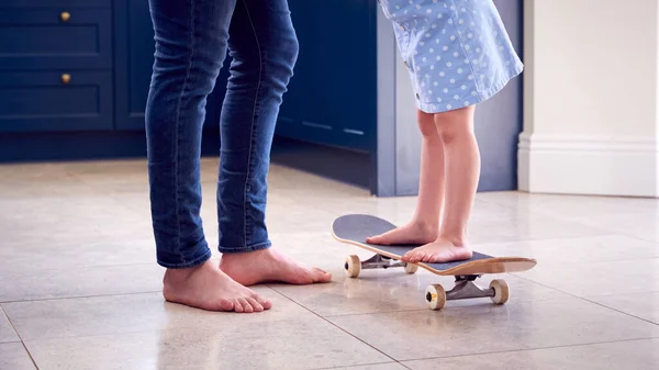 父亲的近照帮助女儿在家中滑板上保持平衡 — 图库照片