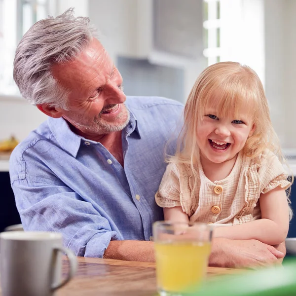 Dziadek Patrząc Śmiechu Wnuczka Siedzi Przy Stole Kuchni — Zdjęcie stockowe