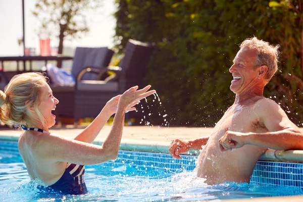退休长者在游泳池内放松彼此在暑假水花中的关系 — 图库照片