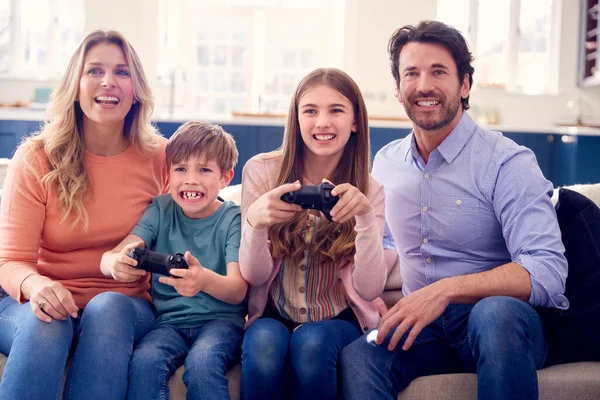 家庭で遊ぶ子供たちとソファに座って楽しむ親ゲームコンソール — ストック写真