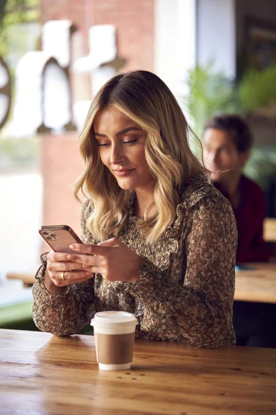 Kahve Dükkanında Masada Oturan Bir Kadın Cep Telefonuna Bakıyor — Stok fotoğraf