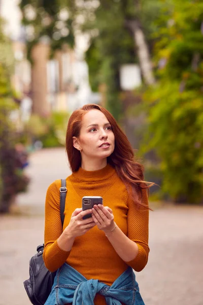 Женщина Блоггер Социальный Деятель Прогуливающаяся Сити Стрит Смотрит Мобильный Телефон — стоковое фото
