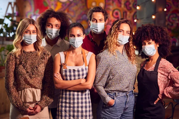 Portrait Of Multi-Cultural Team Of Bar Servers Wearing Face Masks Standing In Bar Or Club