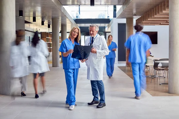 穿着白衣和洗涤器的男医生和女医生在繁忙的医院看数码表 — 图库照片