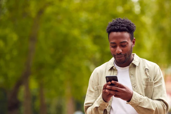 Mężczyzna Vlogger Social Influencer Walking City Park Patrząc Telefon Komórkowy — Zdjęcie stockowe