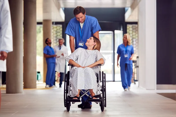 Enfermeira Masculina Vestindo Esfrega Empurrando Paciente Feminino Cadeira Rodas Através — Fotografia de Stock