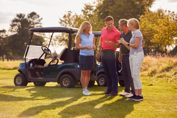 ゴルフバギーで立っている熟女と中年のカップルスコアカードを一緒にチェック — ストック写真