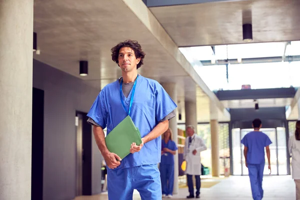 Mannelijke Dokter Draagt Schrobben Dragen Patiëntennotities Lopen Drukke Ziekenhuis — Stockfoto