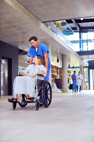 Manlig Sjuksköterska Bär Repor Trycka Kvinnlig Patient Rullstol Genom Sjukhuset — Stockfoto