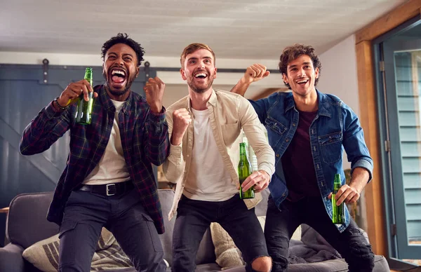 在家看电视上看体育比赛的男性朋友多文化小组用啤酒庆祝进球 — 图库照片