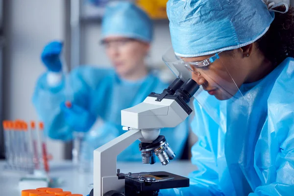 Trabajadoras Laboratorio Que Usan Epi Investigando Laboratorio Con Microscopio —  Fotos de Stock