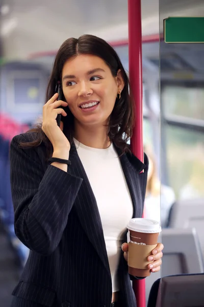 接送咖啡上下班的女商人在火车上用手机聊天 — 图库照片