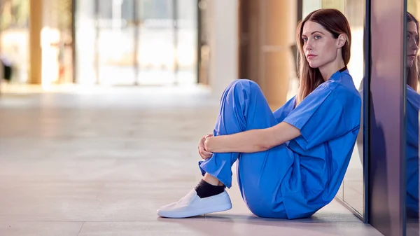 Trött Och Överarbetade Medical Worker Scrubs Sitter Golvet Sjukhuset Korridoren — Stockfoto