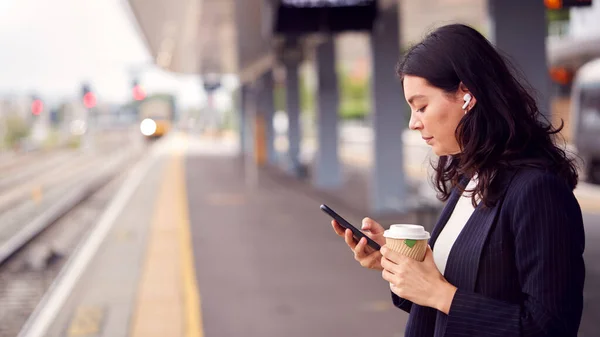 Businesswoman Waiting Train Platform Wireless Earbuds Listens Music Mobile Phone — Stock fotografie